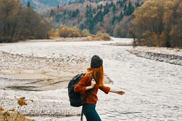 woman hiker backpacker by the river in the mountains in autumn model travel