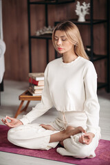 Beautiful young woman enjoying meditation at home