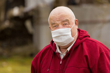 Portrait of an elderly European man with a short haircut in a protective safe medical mask, close-up