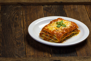 slice of minced meat lasagna and tomato sauce served on white plate with copy space