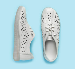 Pale white female shoes on blue backdrop. Flat lay, top view trendy fashion feminine background.