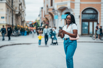 Obraz premium Cheerful african american woman using smartphone
