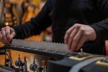 Black electrical guitar in repair service shop with a hands of a guitar luthier