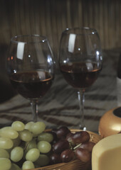Glasses of red wine with two kinds of grapes on wooden background