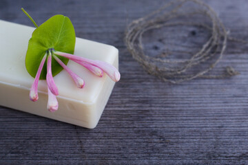 Natural soap with honeysuckle bunch on the grey wooden background. Still life with flowers. 