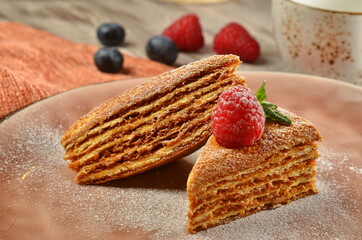 Sweet home layered honey cake on a wooden table with berries closeup