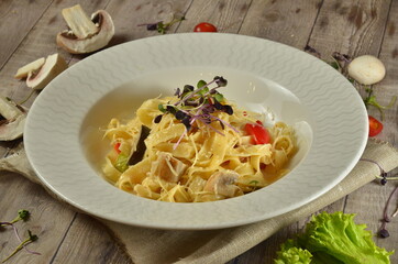 Pasta with mushrooms served in white plate on rustick background