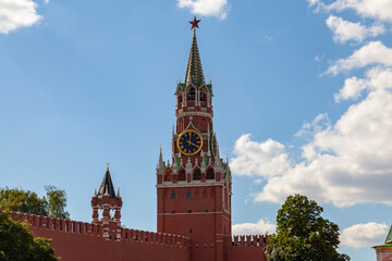 Spasskaya Tower of the Moscow Kremlin against the blue sky in white clouds