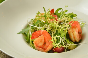 green salad with shrimps on wooden rustic background