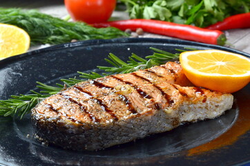 fish steak grill on black plate closeup