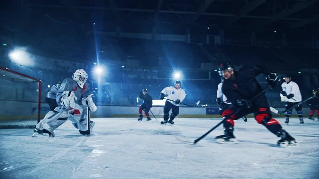 Ice Hockey Arena: Professional Forward Player Breaks Defense, Hitting Puck with Stick Scores Goal, Goalie Missed it. Two Competitive Teams Play Intense Game. Cinematic Slow Motion Long Wide Shot