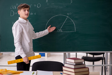 Schoolboy studying geometry in front of blackboard