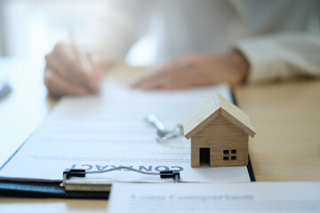Fototapeta premium Following a deal with a broker, a woman signs a contract to rent a house. Real Estate concept.