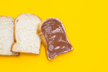 Bread with sweet chocolate hazelnut on yellow background.