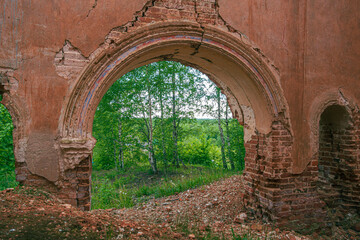 Fototapeta na wymiar The arch is the main gate. An old ruined church. Inside view. Birch trees and a green forest in the background.