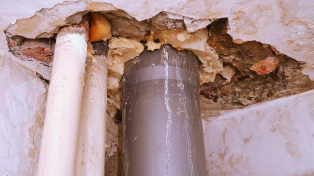 Leaking sewer pipe in the bathroom ceiling. A destroyed ceiling with water stains. Flooded by the neighbors from above.