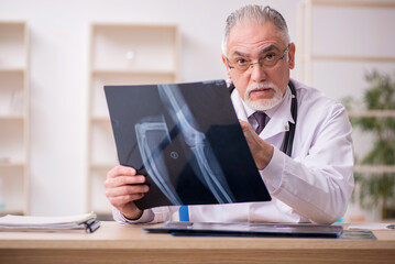 Old male doctor radiologist working in the clinic during pandemi