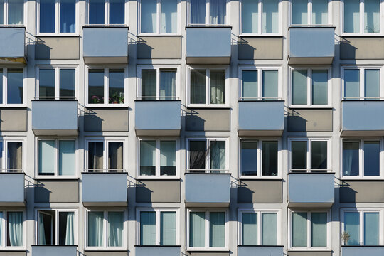 Outdoor exterior front view of modern facade with typical rectangular windows with reflection glass and balconies