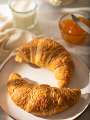 Morning breakfast. Croissants on a white plate, orange jam. White silk tablecloth. Close-up. High angle view. Careful viewing. There are no people in the photo.
