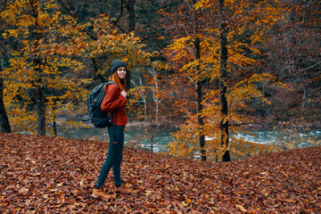 a traveler with a backpack walks in the park in nature near the river in autumn