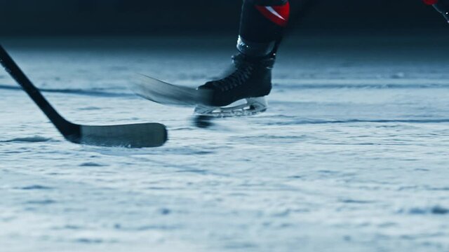 Ice Hockey Rink Arena: Professional Forward Player Masterfully Dribbles, Breaks Defense, Hitting Puck with Stick gives Perfect Pass. Star Teams Play. Cinematic Slow Motion Ground Level Shot