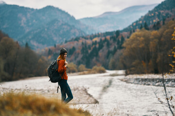 woman on vacation with a backpack on the river bank in the mountains