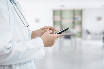 Female Doctor Using Mobile Phone for Medical Appointment Check at Hospital, Medicine Doctor Texting Message on Smartphone in Front of Examination Office. Medic Healthcare and Doctors Service.