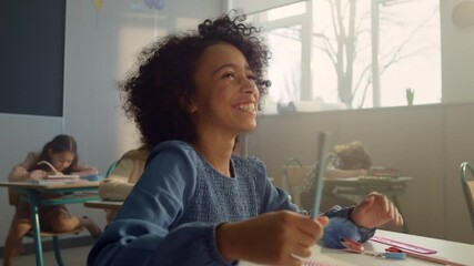 Smiling student raising hand at lesson. Laughing schoolgirl answering question