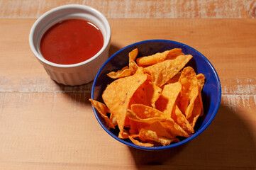A bow of Doritos with a serving of spicy tomato sauce