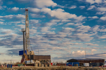 Fototapeta na wymiar A site in the northern tundra at an oil and gas field. Drilling rig for drilling wells. Infrastructure and drilling equipment for drilling operations. Beautiful expressive sky