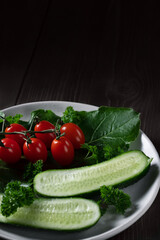 Fresh vegetables and herbs in a plate on a wooden table. Concept of vegetarianism and healthy eating. Copyspace.