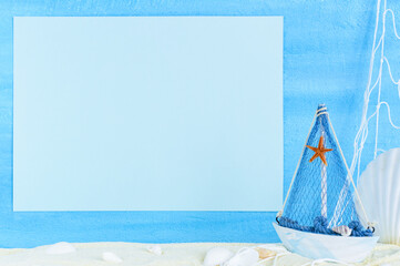 Summer marine background. Ship, fishing net, seashells, starfish on sand with copy space on blue textured backdrop.