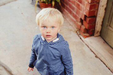 Little blonde toddler boy looking up with big blue eyes and cute expression