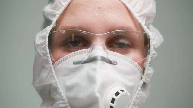 Close-up of overworked doctor or researcher dressed in protective suit ppe mask in laboratory in hospital, female nurse wearing medical uniform, portrait of tired woman chemist in safety glasses. 