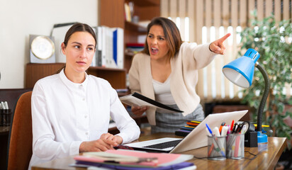 Obraz premium Unhappy woman chief screaming to young female manager during working in office
