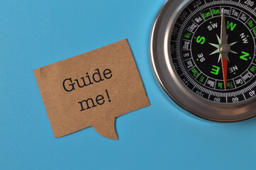 Top view of compass and speech bubble note written with GUIDE ME