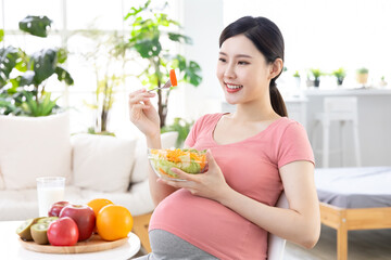 Asian pregnant woman eating salad