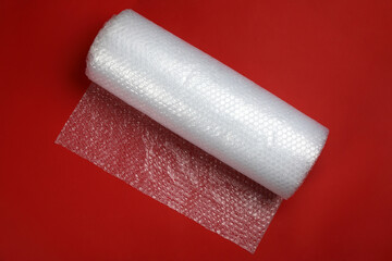 Bubble wrap roll on red background, top view