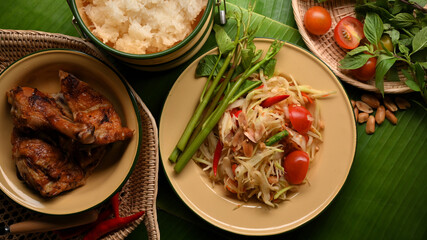 Top view of Somtum or papaya salad with grilled chicken, sticky rice and vegetables