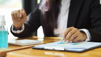 Close up view of businessperson hand with pen pointing on paperwork while working in office