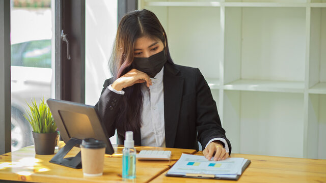 Half-length portrait of businesspeople with face mask working with digital tablet and paperwork