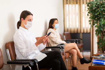 European woman in protective face mask waiting for job interview while sitting at office