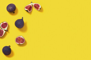 Fresh figs whole and sliced figs on yellow paper surface with copy space. Food background.