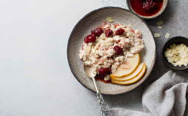 Oat porridge cooked with milk, pears and strawberry jam in rustic  bowl