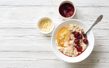 Oat porridge cooked with milk, pears and strawberry jam in white bowl
