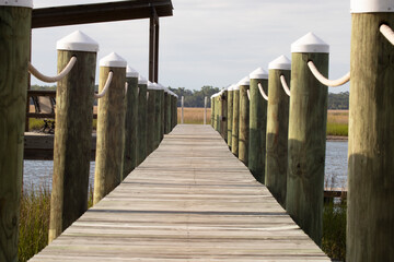 Wooden dock with ropes on sunny day with salt marsh in distance