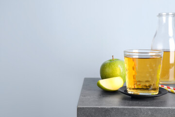 Fresh juice and apples on grey table. Space for text