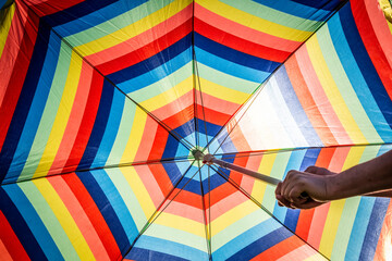 Close-up bright big colorful striped sunny umbrella.