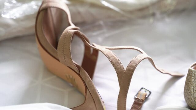 Women's beige strappy high-heeled shoe and sparkling gold flat shoe on white fabric with honeycomb design