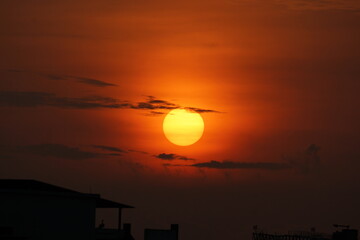 Fototapeta premium Yellow Sun rising in Orange sky with clouds in between